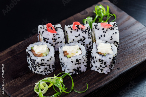 Japanese traditional rolls with seafood and fish, vegetables, on a black background.