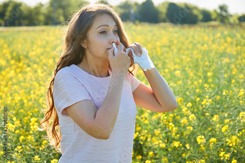 Woman uses a nasal spray, against plant allergies, in a field of flowers