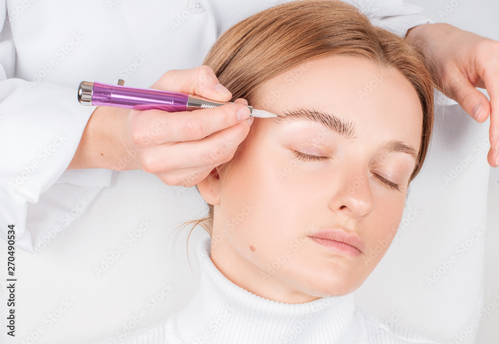 Microblading eyebrows. Attractive woman getting facial care and permanent makeup.