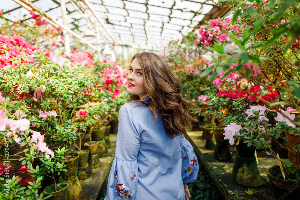 portrait of a young beautiful woman in a blue dress in a beautiful botanic garden with flowers