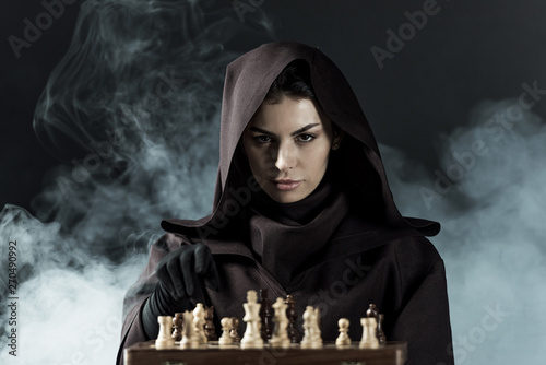 woman in death costume playing chess in smoke on black