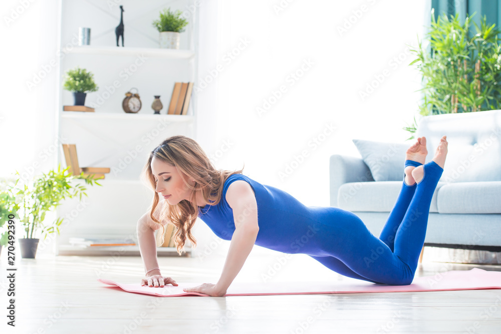 Young athletic girl fitness trainer in blue sports overalls shows morning gymnastic exercises in the interior of the room. Push up, Young athletic girl fitness trainer in blue sports overalls shows morning gymnastic exercises in the interior of the room. Push up,