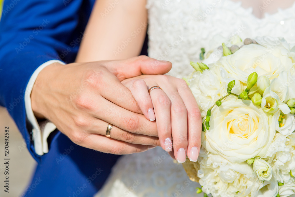 The couple cuddling and holding bridal bouquet. Hands close-up. The couple cuddling and holding bridal bouquet. Hands close-up.