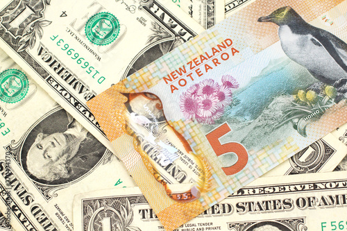 A close up image of a New Zealand five dollar bill with United States one dollar bills in macro photo