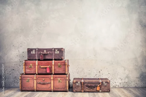 Obraz Vintage klasyczne przestarzałe bagażniki bagażowe z metkami, stare antyczne skórzane walizki z przodu teksturowanej tło wieku betonową ścianę. Koncepcja bagażu podróży. Filtrowane zdjęcie w stylu retro
