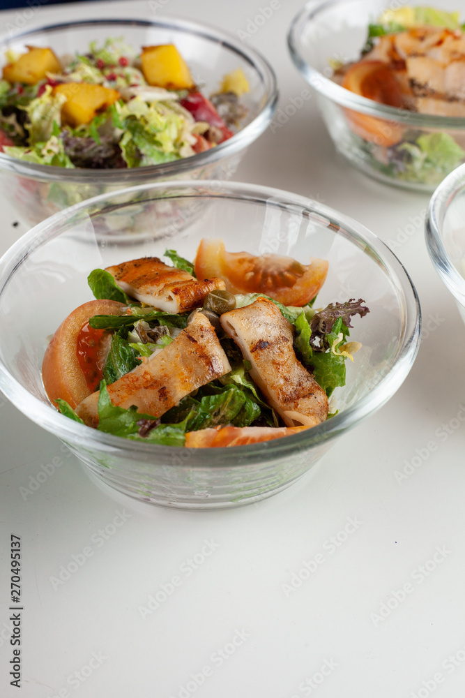 Multiple of salads with fresh veggies in glass bowls on a white table