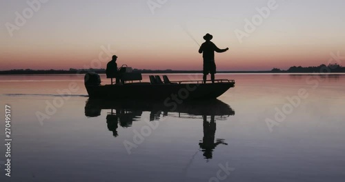 Aerial backlit view of Fisherman fly fishing from a boat on the waterways of the Okavango Delta at sunrise photo