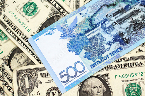 A blue five hundred tenge note from Kazakhstan with American one dollar bills close up in macro