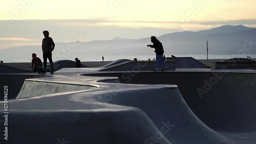 Slow Motion: Skateboarder silhouette skateboarding trick in Venice Beach skate park at sunset. Concept of Los Angeles urban lifestyle, LA tourism travel destination. 