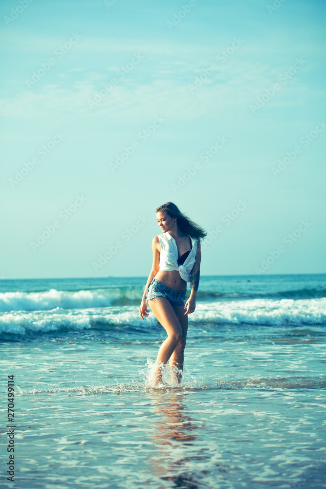 young pretty blond woman at seacoast walking relaxing, fashion lady at sunset, cool vacations
