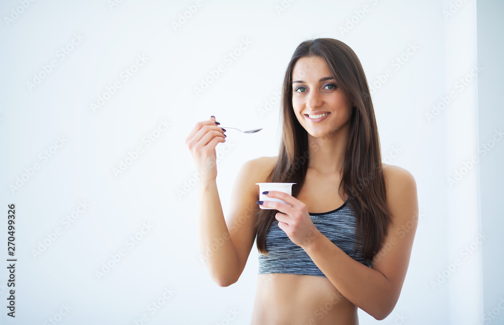 Diet. Happy young woman eating yogurt in kitchen Diet. Happy young woman eating yogurt in kitchen