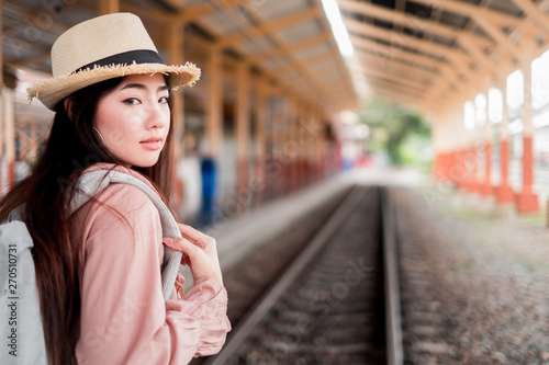 Smiling woman traveler looking camera with backpack on holiday relaxation at the train station,relaxation concept, travel concept