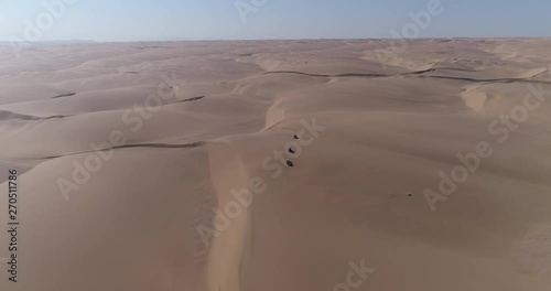 4K aerial zoom in view of 4x4 vehicles driving along the beautiful sand dunes of the Skeleton Coast, Namib desert, Namibia photo