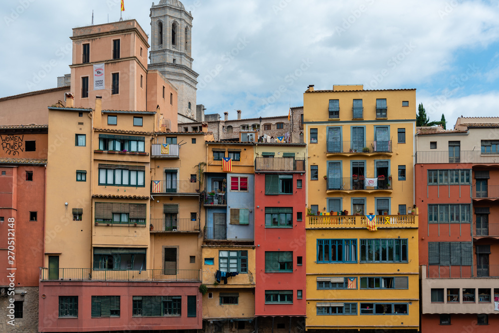 Multi colored houses and spire of Collegiate Church of Sant Felix from bank of the Onyar River, Girona