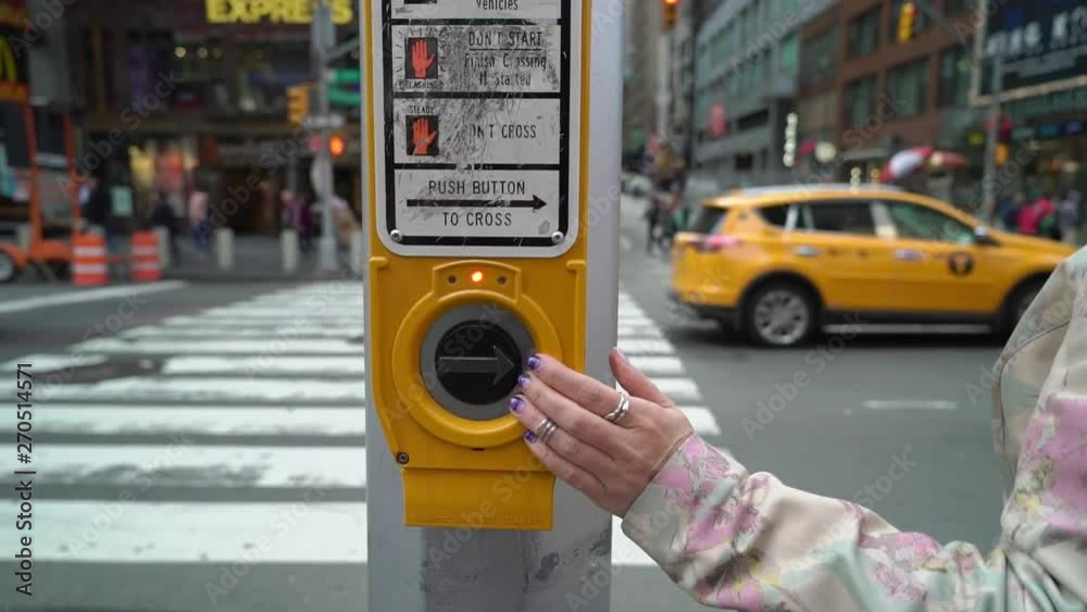 Young woman walking at Manhattan, push button on traffic light and wait for green signal.