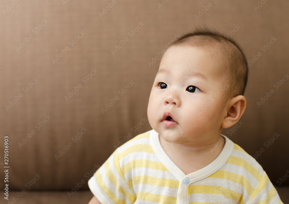 portrait of little small asian baby infant sitting and looking to the left side portrait of little small asian baby infant sitting and looking to the left side