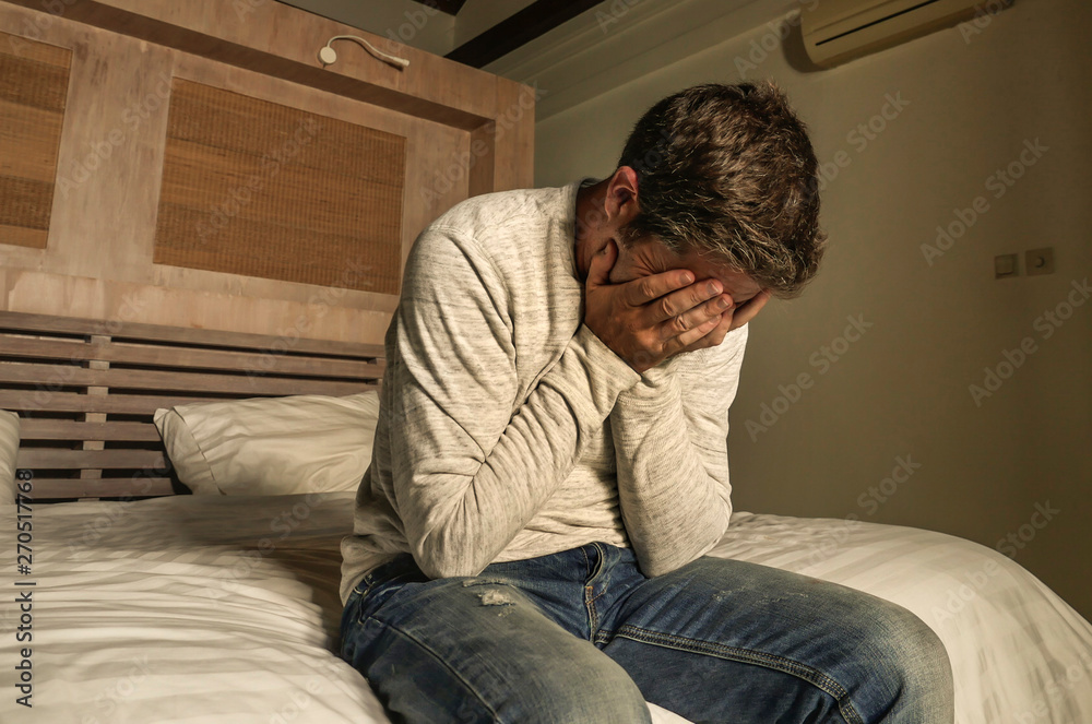 dramatic home portrait of 30s to 40s depressed and desperate man in pain sitting on bed suffering anxiety crisis and depression problem crying sad and frustrated dramatic home portrait of 30s to 40s depressed and desperate man in pain sitting on bed suffering anxiety crisis and depression problem crying sad and frustrated