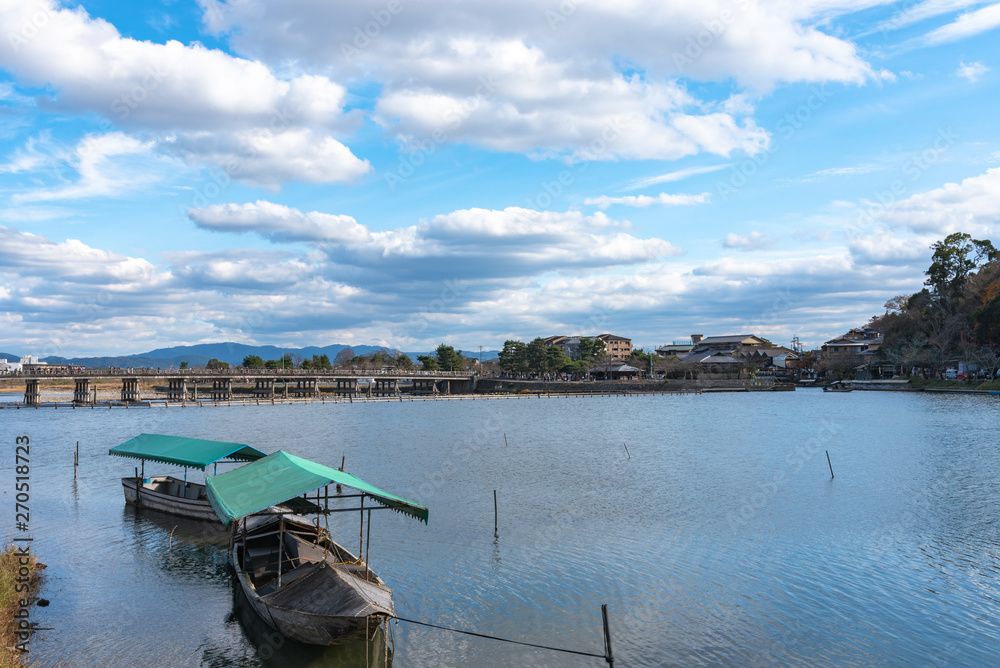 Boat at Hozu-gawa River and Togetsu-kyo bridge with colourful forest mountain background in Arashiyama, Kyoto, Japan. Arashiyama is a nationally designated Historic Site and Place of Scenic Beauty.