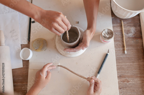 Two pairs of hands make a Cup of clay