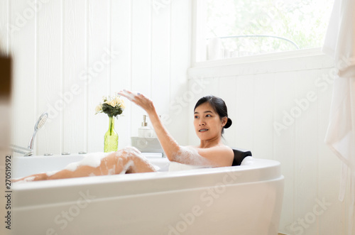 Beautiful asian woman relaxing in bubble bathtub in the morning,Female lying body in water