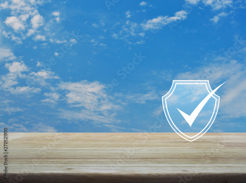 Security shield with check mark flat icon on wooden table over blue sky with white clouds, Technology internet cyber security and anti virus concept