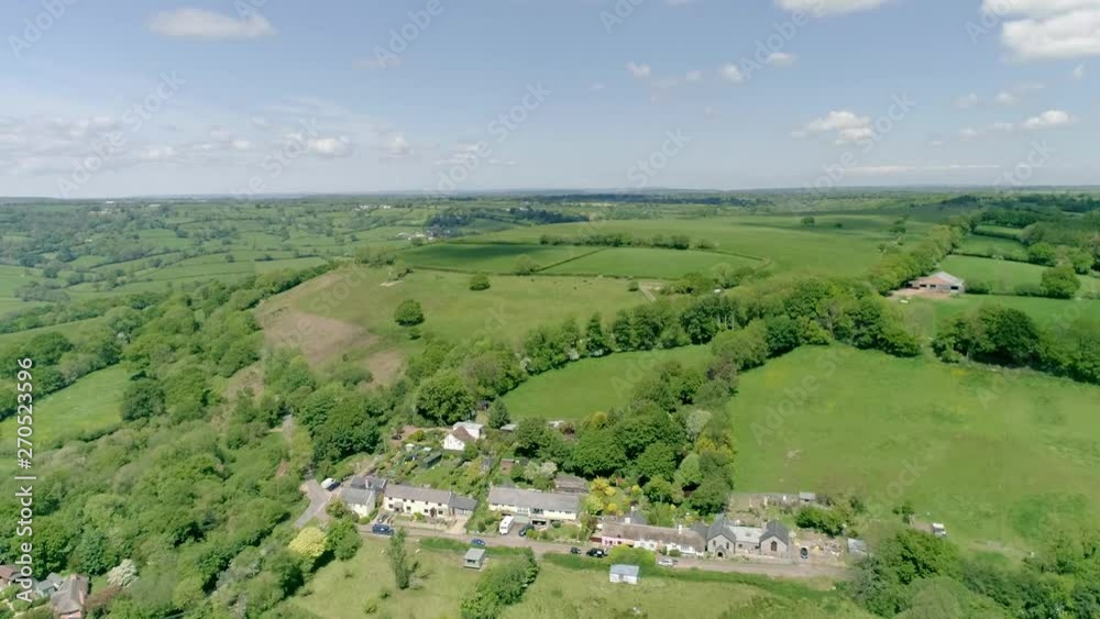 Aerial tracking high above and over a quaint English village nestled on top of a hill in rural Devon Aerial tracking high above and over a quaint English village nestled on top of a hill in rural Devon