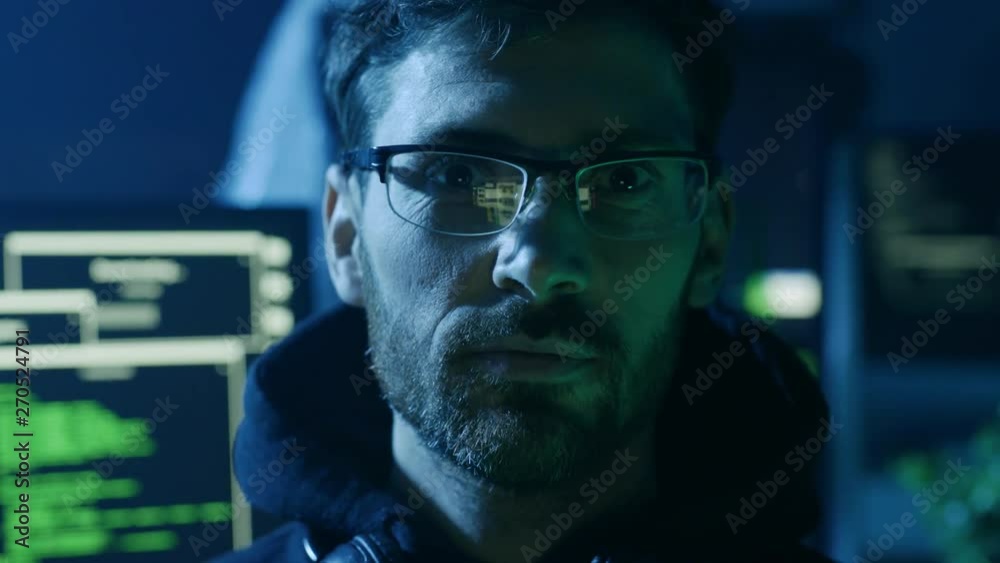Portrait of handsome smart man in glasses working on computer looking at camera. Close-up of IT developer coding technologies in the studio.
