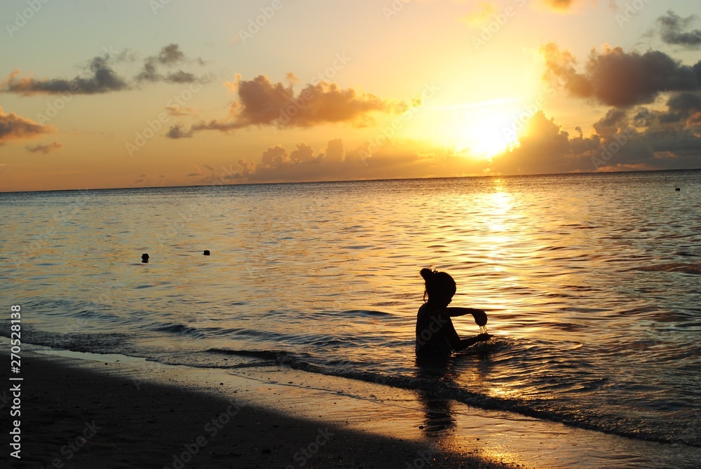 Silhouette of an unrecognizable girl playing with the golden waves on the beach at sunset Silhouette of an unrecognizable girl playing with the golden waves on the beach at sunset