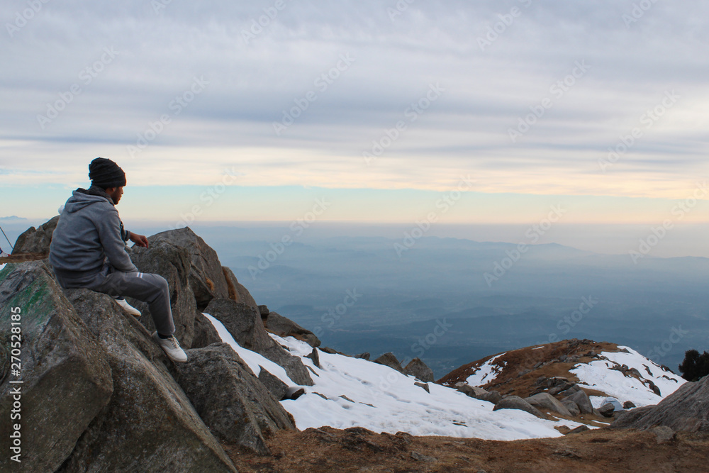 A young trekker looking at the Himalayan landscape. Location: Triund, Himachal Pradesh, India. A young trekker looking at the Himalayan landscape. Location: Triund, Himachal Pradesh, India.