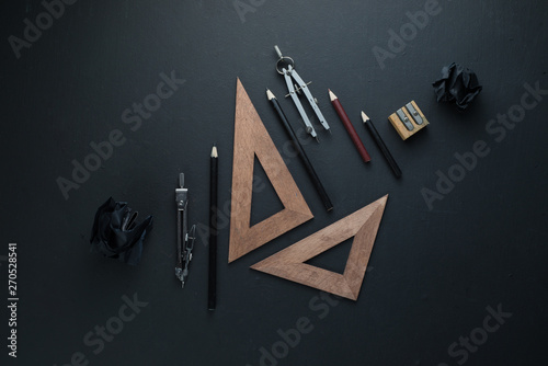 Drawing board flat lay with pencils, compasses, rulers, crumpled paper balls. Dark header for engineering, construction, design with copy space.