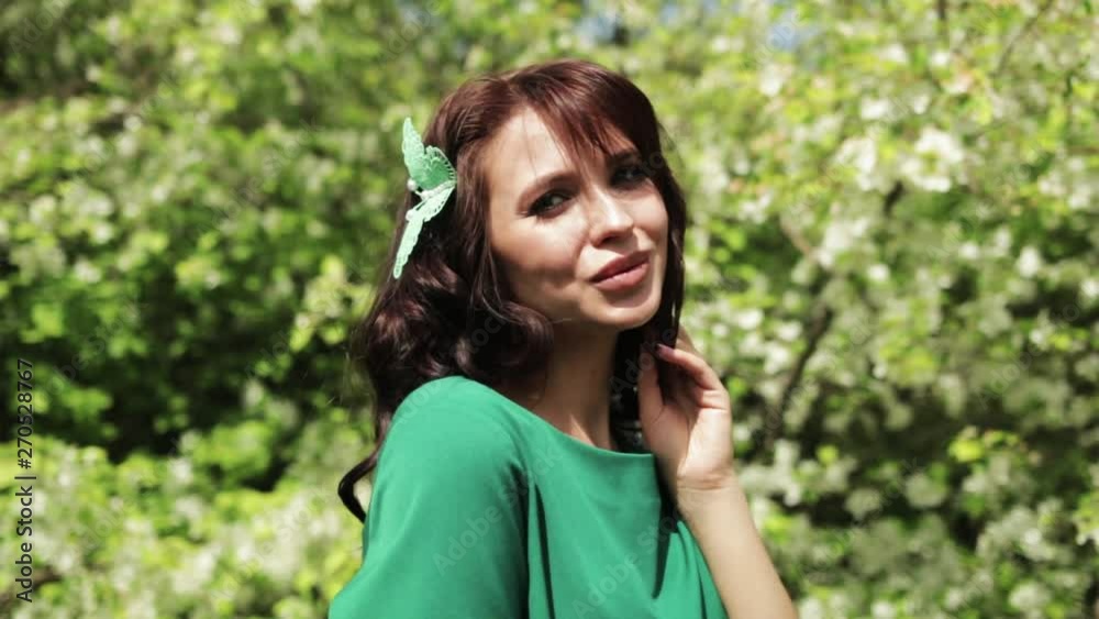 young brunette girl in green dress posing in front of blooming garden, blooming Apple trees, summer, spring, beautiful nature