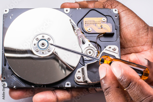 Male technician hand holding and working on dusty computer hard drive with scewdriver photo