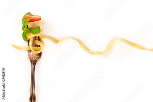 Italian pasta. A fork with a very long pappardelle, basil, cheese, tomato, and pepper, on a white background with a place for text