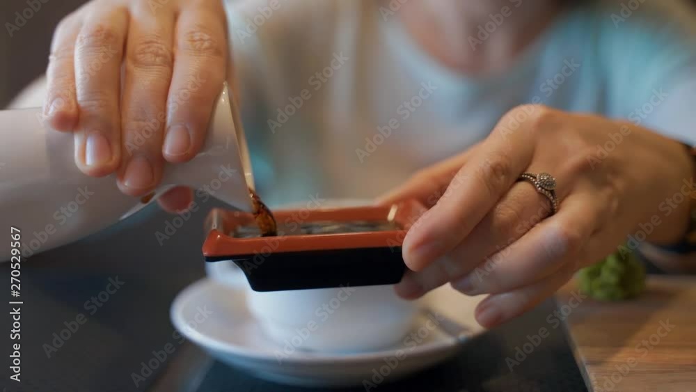 Female hands close-up are pouring soy sauce into a steamer. Female hands close-up are pouring soy sauce into a steamer.