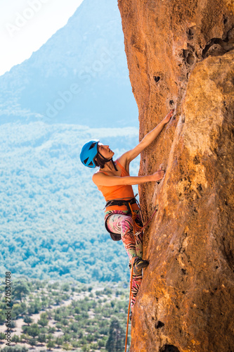 A girl in a helmet climbs a rock.