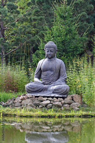 Buddha statue meditating in front of lake  in the nature