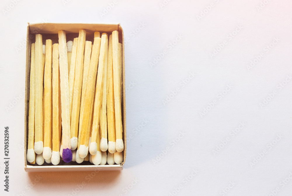 White matches and one match of purple color in a box. Self respect and yourself acceptance concept. Copyspace on the right side of the image for designers. Uniqueness and black sheep concept.
