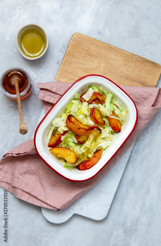 salad with greens and baked peach on marble background with copy space