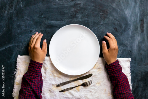 top view of person's hands on the table with empty plate design mock up designs