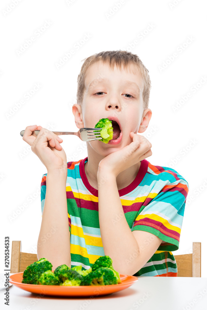 Vertical portrait of a boy who has a diet food, a child eats broccoli on a white background Vertical portrait of a boy who has a diet food, a child eats broccoli on a white background