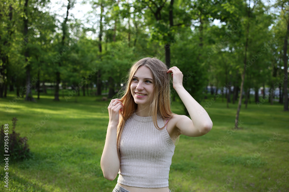 Attractive young girl with blond hair poses beautifully in the city park in the evening. Attractive young girl with blond hair poses beautifully in the city park in the evening.