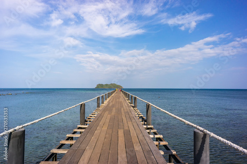 Wood bridge stands into the sea with blue sky