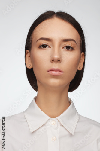 Portrait of a beautiful pacified woman in a white shirt on a light background