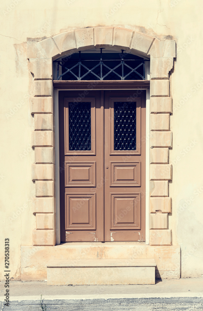 The background old beige stony wall with retro door The background old beige stony wall with retro door