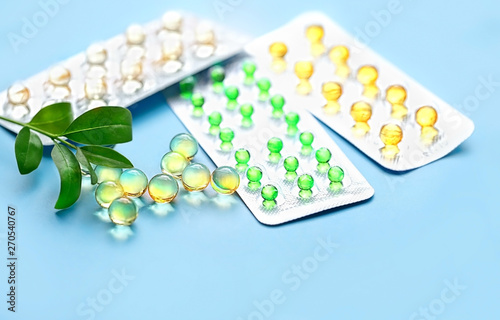 green leaves and blisters medicine on blue background. pill, vitamin dietary supplement, Medical drug. Assorted pharmaceutical medicine pills, tablet, capsules. 