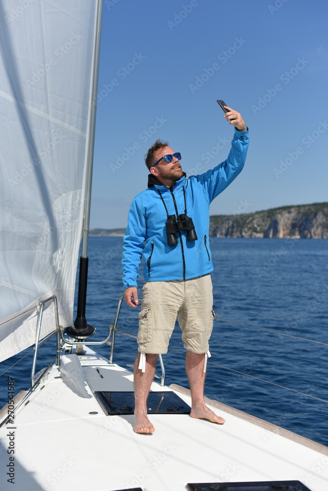 Man sailing with sails out on a sunny day and making selfie