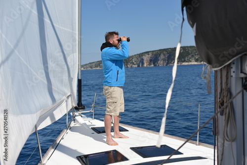 Man sailing with sails out on a sunny day © Visionsi