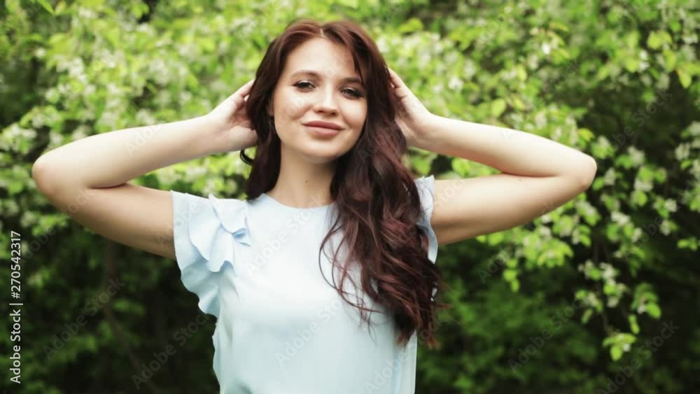 Happy smiling woman in the forest. Sunny summer day. The girl enjoys life.Girl smiling against the background of flowering trees Happy smiling woman in the forest. Sunny summer day. The girl enjoys life.Girl smiling against the background of flowering trees