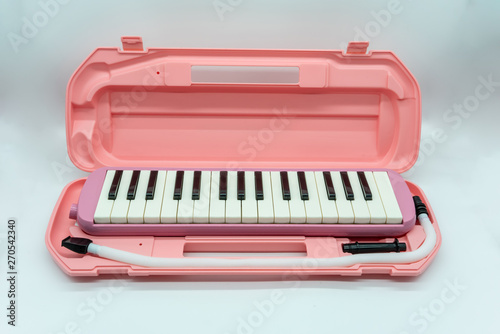 Musical pink melodian with hard plastic case isolated on white photo