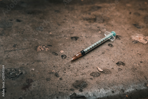 Heroin syringe on rough concrete, dirty background